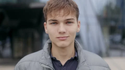 One young handsome man looking directly at camera near glass urban building. Stock-Footage 332765685