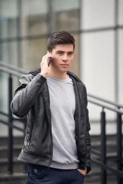 One young handsome man posing outdoors, wearing jacket, talking over smartpho Foto stock