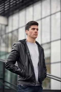 One young handsome man posing outdoors, wearing jacket, casual clothes, upper Stock Photos