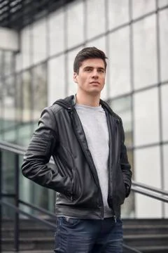 One young handsome man posing outdoors, wearing jacket, casual clothes, upper Stock Photos