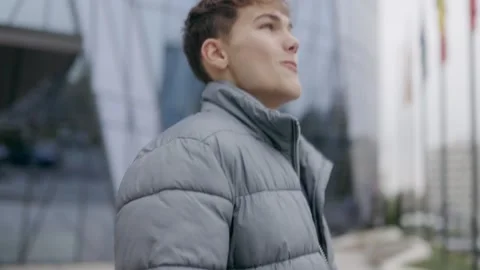 One young happy man smiling and walking near modern city building exterior. Stock Footage 332765672