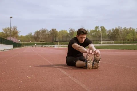 One young man, athlete stretching two legs Stock Photos