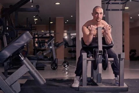 One young man bodybuilder, exercise equipment, bicep curl, indoors gym. full  Stock Photos