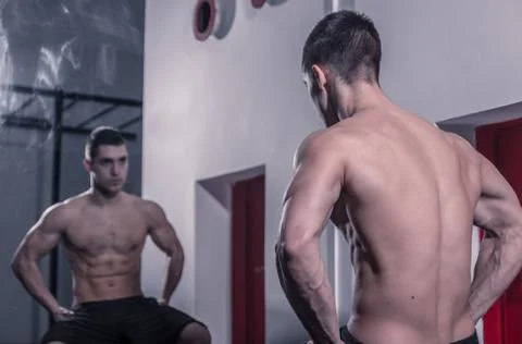 One young man bodybuilder looking at himself in mirror Stock Photos
