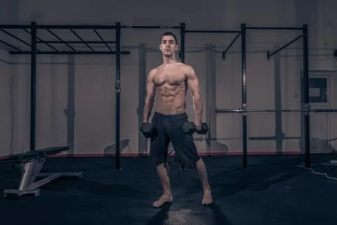 One young man, bodybuilder posing, holding dumbbells Stock Photos