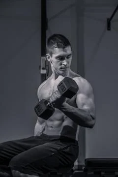 One young man, bodybuilder training dumbbell biceps Stock Photos