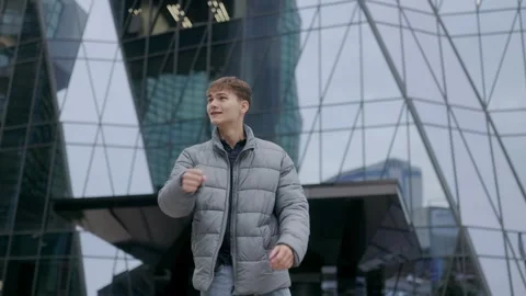 One young man jumping and cheering outdoor near glass building in urban style. Stock Footage 332765763