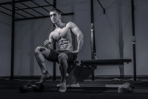 One young man, low angle view, bodybuilder muscular sitting posing Stock Photos