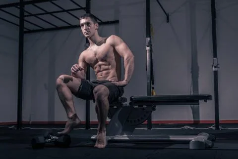 One young man, low angle view, bodybuilder muscular sitting posing Stock Photos
