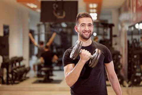 One young man, ordinary average looking, one arm dumbell exercise, smirking,  Stock Photos