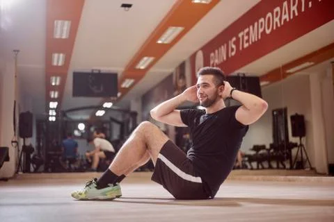 One young man, ordinary average man, exercise abs, sideways, sitting on floor Stock Photos