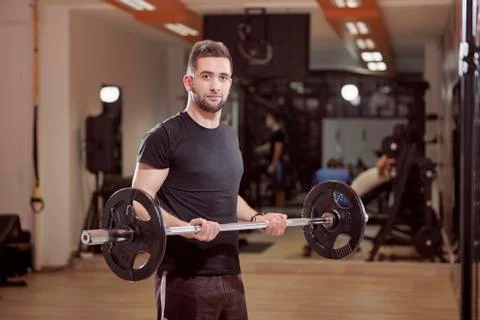 One young man posing, ordinary average looking, holding barbell with weights, Stock Photos