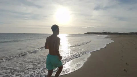 One young man running and enjoying summer in a beach alone with sunset Vídeos de archivo 143362859