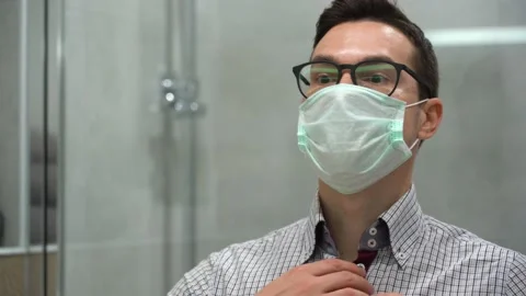 One young worker guy wear face mask, look, admires himself in mirror close up.  Stock Footage 131461743