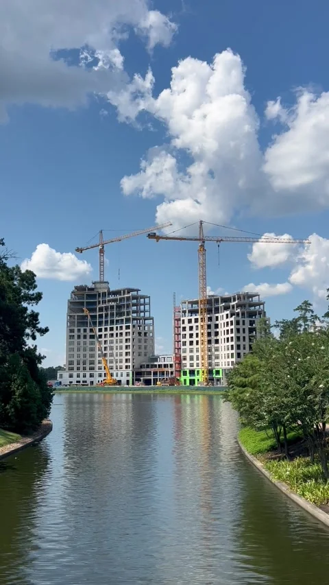 Ongoing construction of two buildings by a lake Stock Footage 336975404