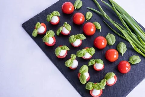 Onion, composition of vegetables, tomatoes, mozzarella on a stone black tile Stock Photos
