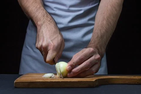 Onion on a dark background. The cook cuts the onion on a black background. Stock Photos