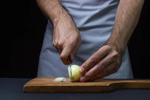 Onion on a dark background. The cook cuts the onion on a black background. Stock Photos