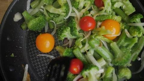 Onions, broccoli and beans vegetables are cooking in a pan, view from above Stock Footage