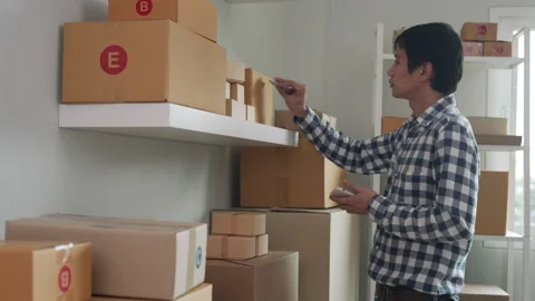 Online business owner write down delivery details and tag on the box for deli Stock Footage 164670916