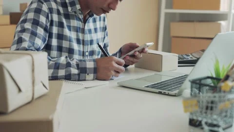 Online business owner write down delivery details and tag on the box for deli Stock Footage 164671728