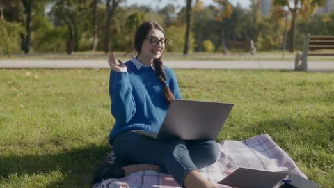 Online chat and study session for student girl in autumn park Stock Footage 300264369