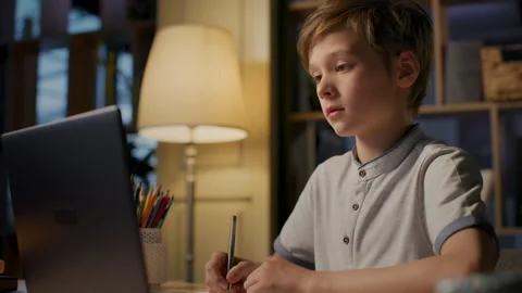 Online education of smart child using laptop at evening home. Remote study of li Stock Footage 199484782