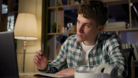 Online education of university student using laptop in evening room. Remote stud Stock Footage 199484772