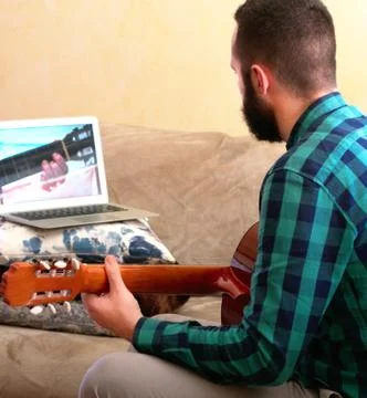 Online learning concept. Young man concentrating as he learns to play the gui Stock Photos