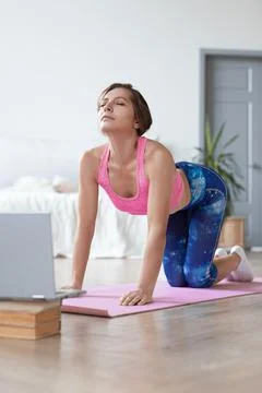Online Pilates workout using a tutorial on the Internet. Woman flexes her back 写真素材