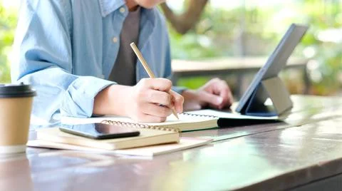 Online studying class, Student man hand writing on notebook while using digit Stock-Fotos