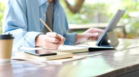 Online studying class, Student man hand writing on notebook while using digit Stock Photos