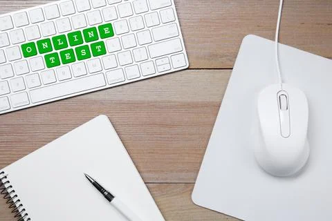 Online test. Computer keyboard with words, mouse and stationery on wooden t.. Stock Photos