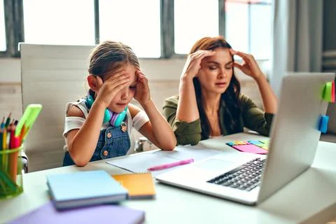 Online training. Very difficult lessons. Schoolgirl with her mother listen to Stock Photos