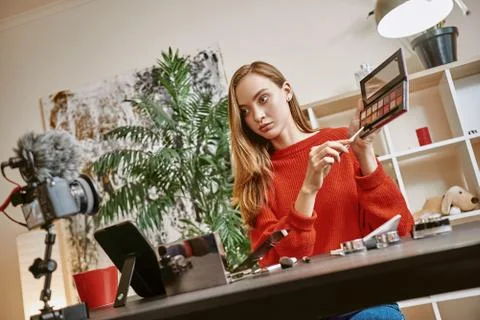 Online tutorial. Cute and young blogger presenting a makeup palette on camera Foto stock