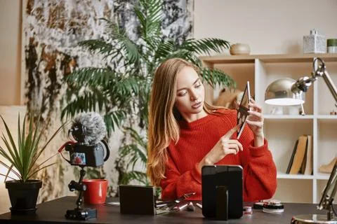 Online tutorial. Young attractive woman showing a makeup palette on camera and Stock Photos