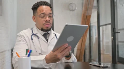 Online Video Chat by Hispanic Young Doctor via Tablet Vídeo Stock 305737726