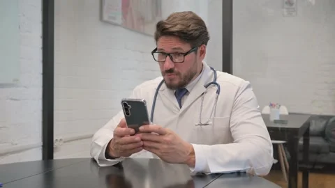 Online Video Chat by Middle Aged Doctor on Phone in Clinic Stock Footage 310166497