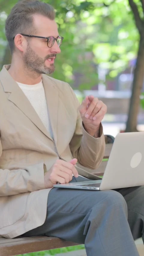 Online Video Chat by Middle Aged Man on Laptop while Sitting Outdoor on Bench, Video stock 319013732