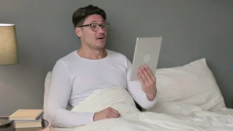 Online Video Chat on Tablet by Middle Aged Man in Bed Stockbeeldmateriaal 142378200