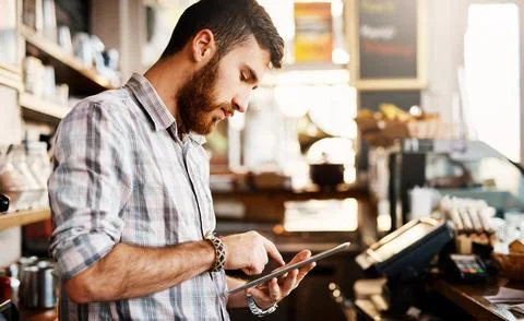 Online is where the buzz is. a young man using a digital tablet while working in Stock Photos
