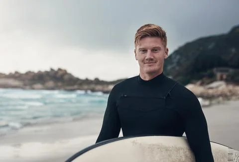 The only thing Im chasing is waves. a man holding his surfboard while at the Stock Photos