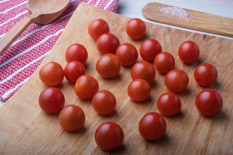 Only washed small red cherry tomatoes on a natural wooden surface, next to it 스톡 사진