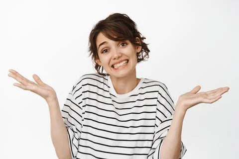Oops sorry my mistake. Cute awkward woman shrugging shoulders and smiling Stock Photos