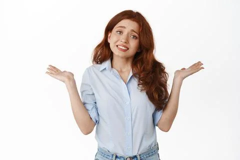Oops sorry. Silly redhead girl trainee shrugging shoulders confused, being Stock Photos