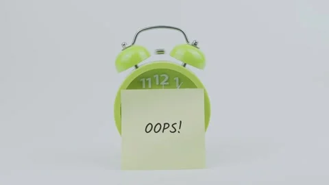 Oops word on sticky note in front of green clock and ringing on white Stock Footage 313908797