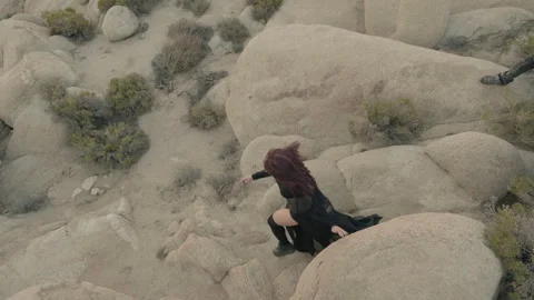 Op down shot of a Punk man chasing Goth woman in rocky mountains Vídeo Stock 293275459