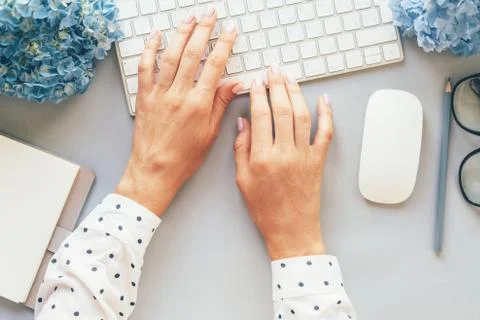 Op view of hands in a polka-dot shirt typing on a computer keyboard Foto stock