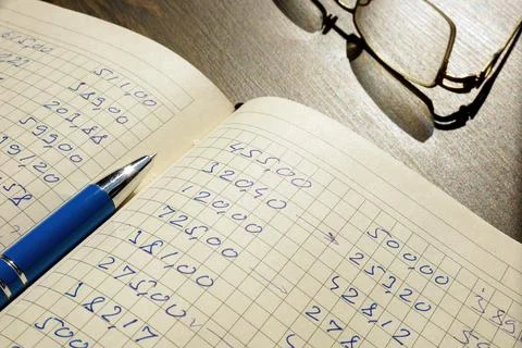 Open accounting book with data and pen. Home finances calculations concept. Stock Photos