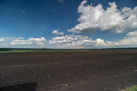 Open agricultural field under dramatic cloudscape Stockfoto's